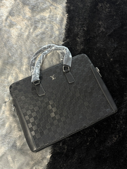 Louis Vuitton Damier Graphite laptop bag features a black checkered pattern and a prominent silver LV logo